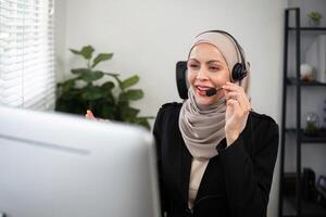 Jeune musulman femmes portant hijab télémarketing ou appel centre agent avec casque travail sur soutien hotline à Bureau photo
