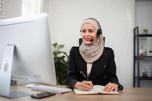 Jeune musulman femmes portant hijab télémarketing ou appel centre agent avec casque travail sur soutien hotline à Bureau photo