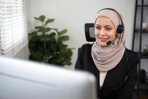 Jeune musulman femmes portant hijab télémarketing ou appel centre agent avec casque travail sur soutien hotline à Bureau photo