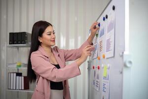 asiatique femme d'affaires ou femelle financier analyste financier une analyse et investissement plan sur une planche à Bureau photo