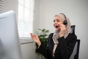 Jeune musulman femmes portant hijab télémarketing ou appel centre agent avec casque travail sur soutien hotline à Bureau photo