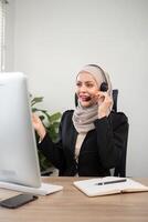 Jeune musulman femmes portant hijab télémarketing ou appel centre agent avec casque travail sur soutien hotline à Bureau photo