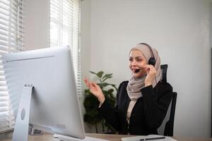 Jeune musulman femmes portant hijab télémarketing ou appel centre agent avec casque travail sur soutien hotline à Bureau photo