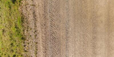 vue de au dessus sur texture de humide boueux route avec tracteur pneu des pistes dans campagne photo