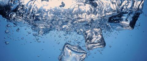 l'eau éclabousser et la glace cube. la glace éclabousser dans une verre de l'eau. sous-marin verser la glace cubes chute dans clair arrosage Contexte. rafraîchissant refroidissement en buvant. glaces dans une verre avec bleu Contexte photo