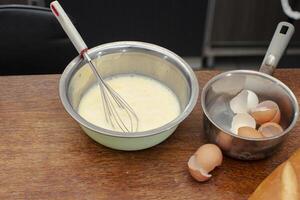 dans une bol là est une mélange pour fabrication un omelette et coquilles pour des œufs. photo