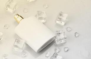 bouteille blanche de tapis de parfum féminin, photographie objective de la bouteille de parfum dans des glaçons et de l'eau sur une table blanche. vue d'en-haut. photo de produit maquette, concept de fraîcheur