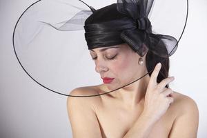 belle femme aux lèvres rouges et aux yeux fermés avec un regard triste et un chapeau noir. mode rétro photo