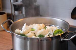 brocoli et choufleur sont à la vapeur dans une casserole - en bonne santé régime, bébé nourriture, cuisine dans une bateau à vapeur photo