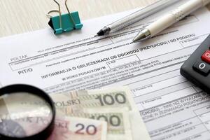 information à propos déductions de le revenu et impôt, pit-o forme sur comptable table avec stylo et polonais zloty argent factures photo