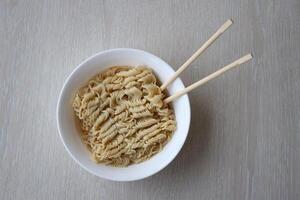 bol de instant cuisine nouilles avec en bois baguettes sur blanc en bois table photo