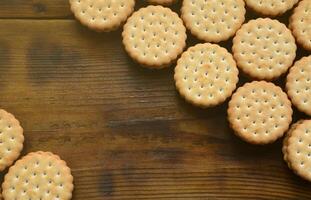 un biscuit sandwich rond fourré à la noix de coco se trouve en grande quantité sur une surface en bois marron. photo de friandises comestibles sur un fond en bois avec espace de copie