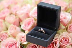 or diamant engagement bague dans noir boîte Cas parmi gros montant de des roses dans gros bouquet proche en haut photo