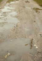 photo d'un fragment d'une route détruite avec de grandes flaques d'eau par temps de pluie