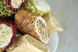 beaucoup Rouleaux de turc délice avec différent les saveurs et plombages dans blanc assiette sur tableau. coupes de Turc lokumu photo