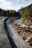 le barrage est protecteur, béton chape de le rivière littoral, protection de le chaussée de inondation, Montagne rivière, Humain intervention dans la nature. photo