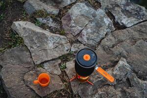 Haut vue de randonnée ustensiles, Orange thé agresser permanent sur une calcul, pot pour ébullition eau, ensemble pour cuisine dans le forêt photo