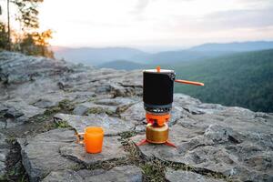 un soir de tranquillité dans le montagnes avec une agresser de fort thé à le coucher du soleil. camping sur le Montagne cuisine camping, trekking dans nature, magnifique voir, ustensiles pour alimentaire. photo