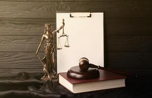 dame justice ou justitia la déesse romaine de la justice. statue sur livre brun avec marteau de juge sur fond de papier vierge avec espace pour copie. concept de procès judiciaire, de procédure judiciaire et de travail des avocats photo