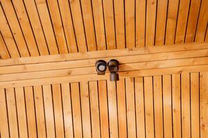 plafond les lampes sur le toit de le loger, intérieur éclairage de une pays loger, en bois plafond, place éclairage, conception de lumière sur le façade de le bâtiment. photo