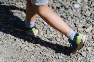 bébé jambes Haut voir, garçon en marchant sur le route, pied dans espadrille, court marcher, bébé jambes, minimalisme de le Humain corps, ombre de le enfant photo