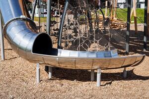 métal enfants rond glisser, terrain de jeux pour enfants, ville parc dans une moderne style, brillant chrome, inoxydable acier. photo