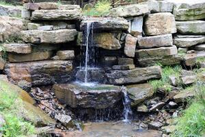 proche en haut de une petit cascade effusion plus de mousse couvert rochers dans régional parc. Fait main rivière cascade photo