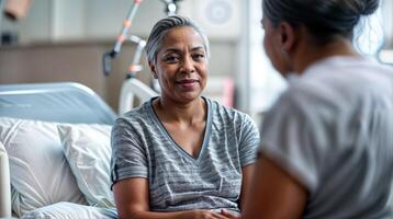 personnes âgées africain femme dans hôpital lit ayant une conversation avec soins de santé professionnel photo