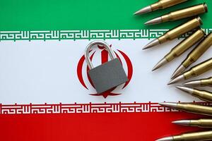 petit cadenas mensonges sur pile de iranien drapeau et fusil balles proche en haut. les sanctions, interdire ou embargo dû à armé la terreur photo