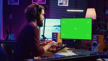 la musique producteur apprentissage à utilisation mélange console avec en ligne Didacticiel sur ordinateur, à la recherche à isolé écran vert afficher. du son ingénieur les pratiques édition des sons dans le sien Accueil studio. caméra un. photo