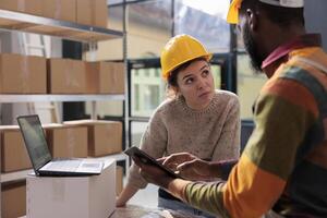 diverse magasin équipe vérification en ligne ordres sur tablette ordinateur, en cours d'analyse des produits pour inventaire rapport dans entrepôt. espace de rangement pièce des employés travail à clients paquets en train de préparer transport photo