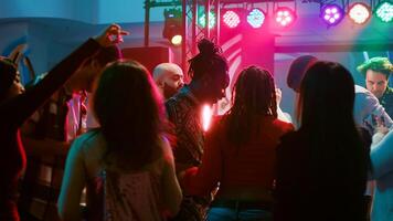 Jeune adultes Faire cool Danse se déplace à club, faire la fête ensemble et ayant amusement sur électronique musique. diverse foule de gens profiter nuit en dehors avec vivre performance sur Danse sol. photo