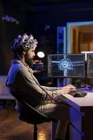 ordinateur ingénieur avec eeg casque sur l'écriture code permettant lui à transfert esprit dans virtuel monde, devenir un avec ai. fou scientifique en utilisant neuroscientifique technologie à Gain superintelligence photo