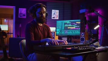 auteur compositeur musicien en jouant guitare et électronique piano clavier dans Accueil studio, enregistrement acoustique avec moniteurs mélange équipement à produire Nouveau moderne Chansons. égaliseur et choucas logiciel. caméra b. photo