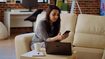 content de bonne humeur la personne bavardage avec en ligne copains plus de le téléphone, profiter se dans accueillant élégant maison. divertir femme défilement sur social médias alimentation, caméra b panoramique coup photo