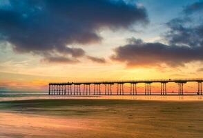 le coucher du soleil jetée à brûlure de sel par le mer, Nord Yorkshire, Royaume-Uni photo