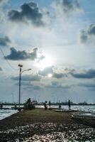 Jepara, central Java, avril 7, 2024 -les pêcheurs à le jepara jetée avec une le coucher du soleil ciel comme le Contexte avec gratuit espace pour photocopies. la nature concept pour publicité. photo