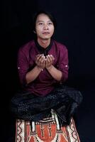 de face vue de une homme prier sur une prière tapis avec une noir Contexte. photo