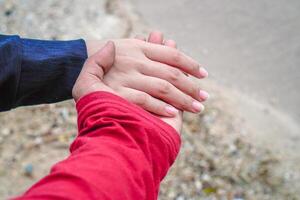 le mains de une couple en portant mains contre le Contexte de plage sable. photo