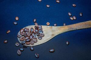 noir café des haricots sont vu proche en haut avec une en bois cuillère sur une noir chiffon. photo