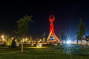 Ouzbékistan, Tachkent - septembre 15, 2023 illuminé monument de indépendance dans le forme de une stèle avec une humo oiseau dans le Nouveau Ouzbékistan parc à la nuit dans l'automne. photo