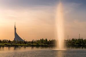 Ouzbékistan, Tachkent - septembre 15, 2023 monument de indépendance dans le forme de une stèle avec une humo oiseau sur une le coucher du soleil avec spectaculaire cloïdes dans le Nouveau Ouzbékistan parc. photo