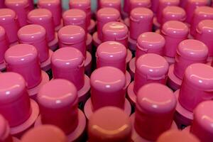 une de haut en bas vue de rose shampooing bouteille casquettes sur une boutique étagère. le uniforme Couleur crée une cohésif regarder, avec le casquettes soigneusement arrangé dans Lignes. photo