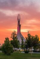 Ouzbékistan, Tachkent - septembre 15, 2023 monument de indépendance dans le forme de une stèle avec une humo oiseau sur une crépuscule avec spectaculaire cloïdes dans le Nouveau Ouzbékistan parc. photo