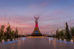 Ouzbékistan, Tachkent - septembre 15, 2023 monument de indépendance dans le forme de une stèle avec une humo oiseau sur une crépuscule avec spectaculaire cloïdes dans le Nouveau Ouzbékistan parc. photo