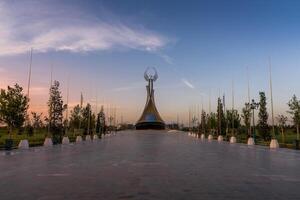 Ouzbékistan, Tachkent - septembre 15, 2023 monument de indépendance dans le forme de une stèle avec une humo oiseau sur une crépuscule avec spectaculaire cloïdes dans le Nouveau Ouzbékistan parc. photo