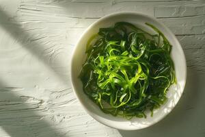 Haut vue à une assiette avec vert salade fabriqué de chukka algue sur une en bois tableau, illuminé par brillant lumière du soleil. végétalien Fruit de mer. photo