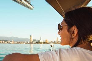 femme est assis dans de face de le bateau et regards à bleu noir mer horizon après le le coucher du soleil. bateau voyages Géorgie , sens de destination et liberté concept photo