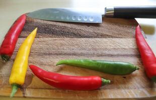 vue de dessus et en perspective du piment et du couteau en acier sur une planche à découper en bois avec un arrière-plan isolé photo