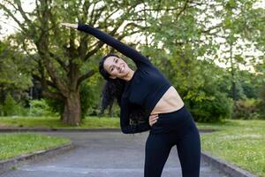 souriant femme performant une côté étendue dans une vert parc paramètre, mettant en valeur une en bonne santé mode de vie et Extérieur aptitude routine. photo